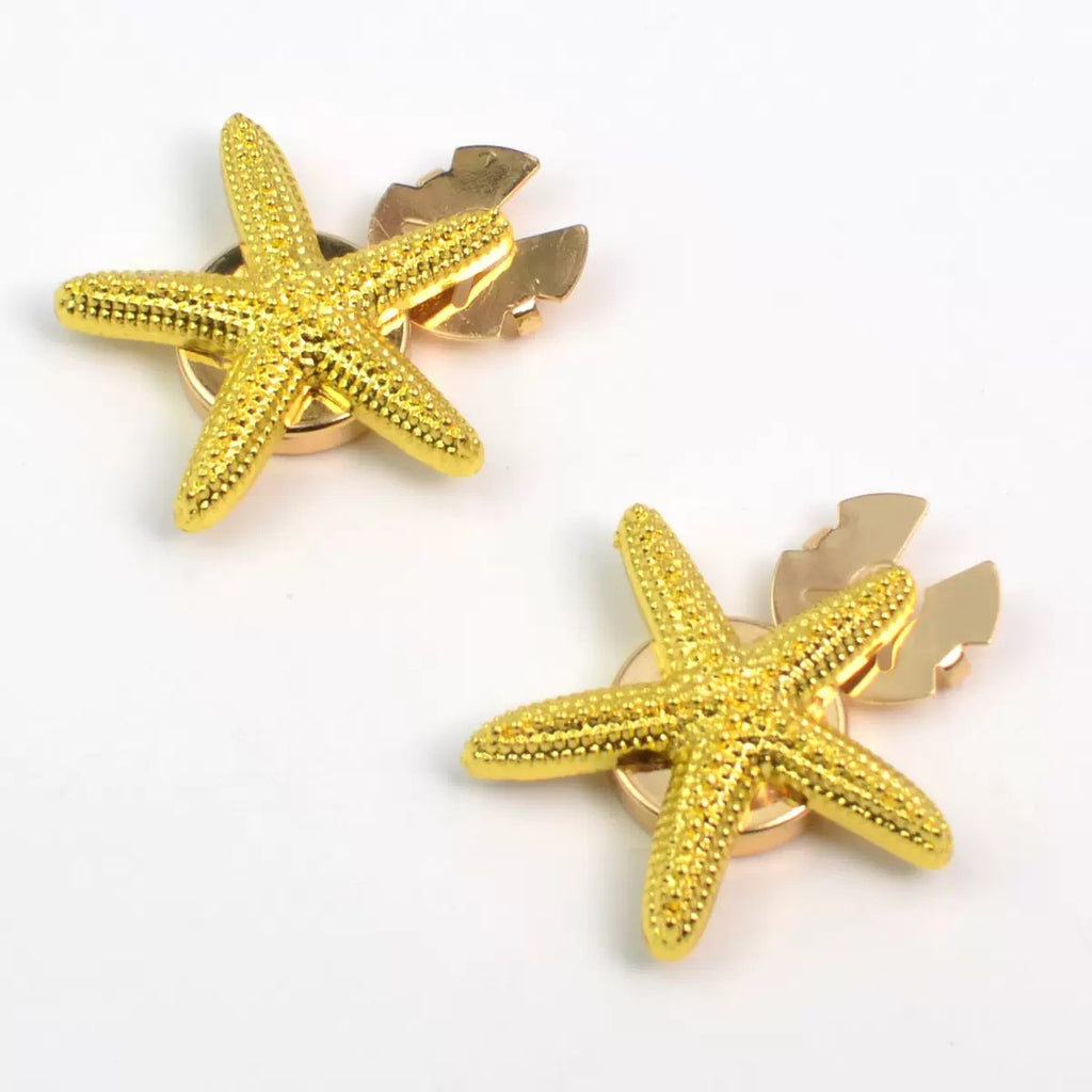 Gold starfish stud earrings pair on white background