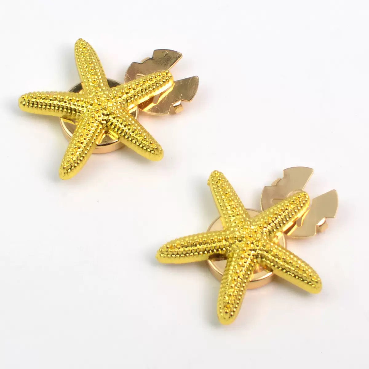 Gold starfish stud earrings pair on white background