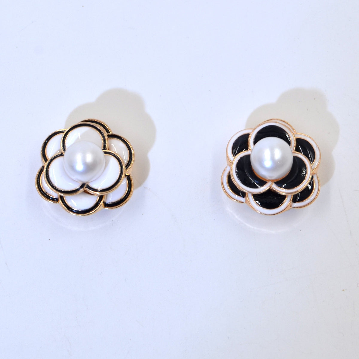 Camellia pearl stud earrings in black and white enamel with gold trim, shown in two colorways