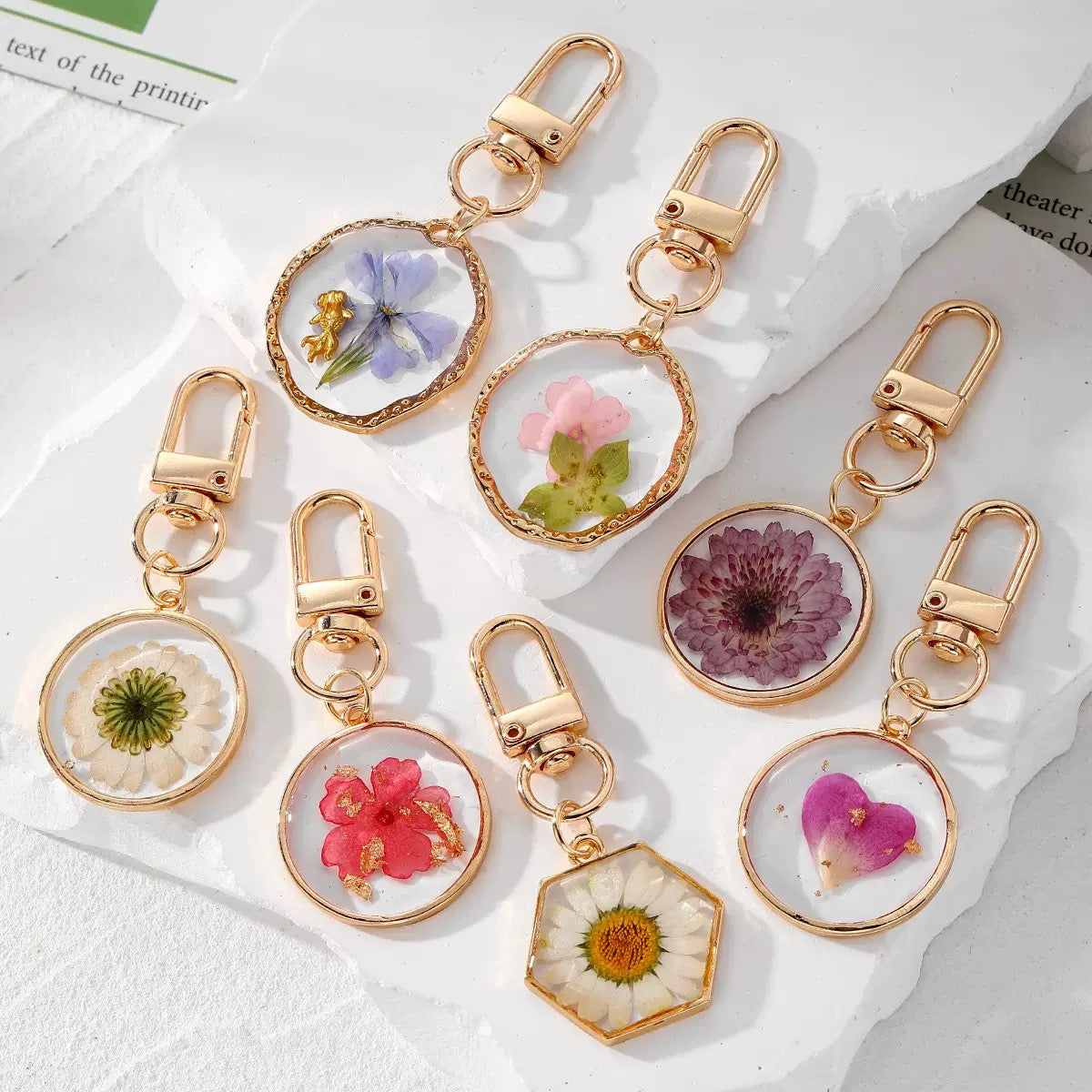 Dried flower resin keychains in gold-tone frames with various pressed flowers