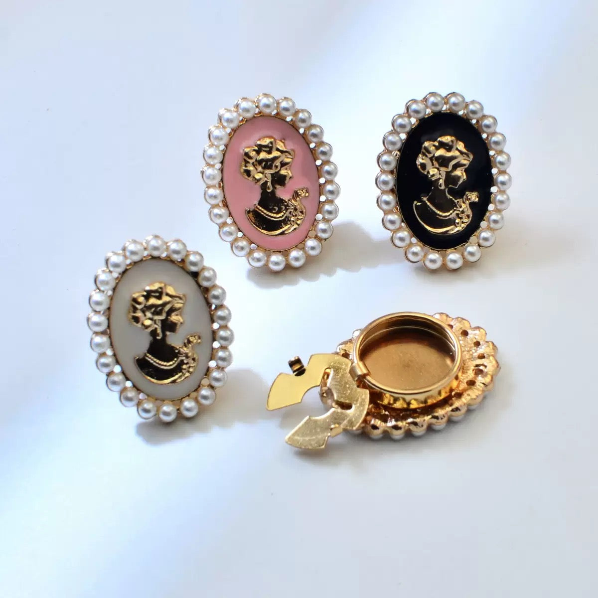 Vintage pearl cameo brooches in white, pink, and black colorways with gold-tone setting